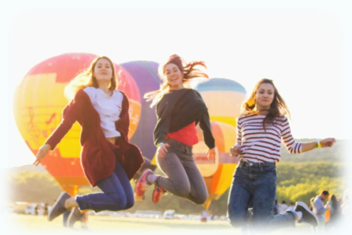 Three friends jumping in the air with balloons
