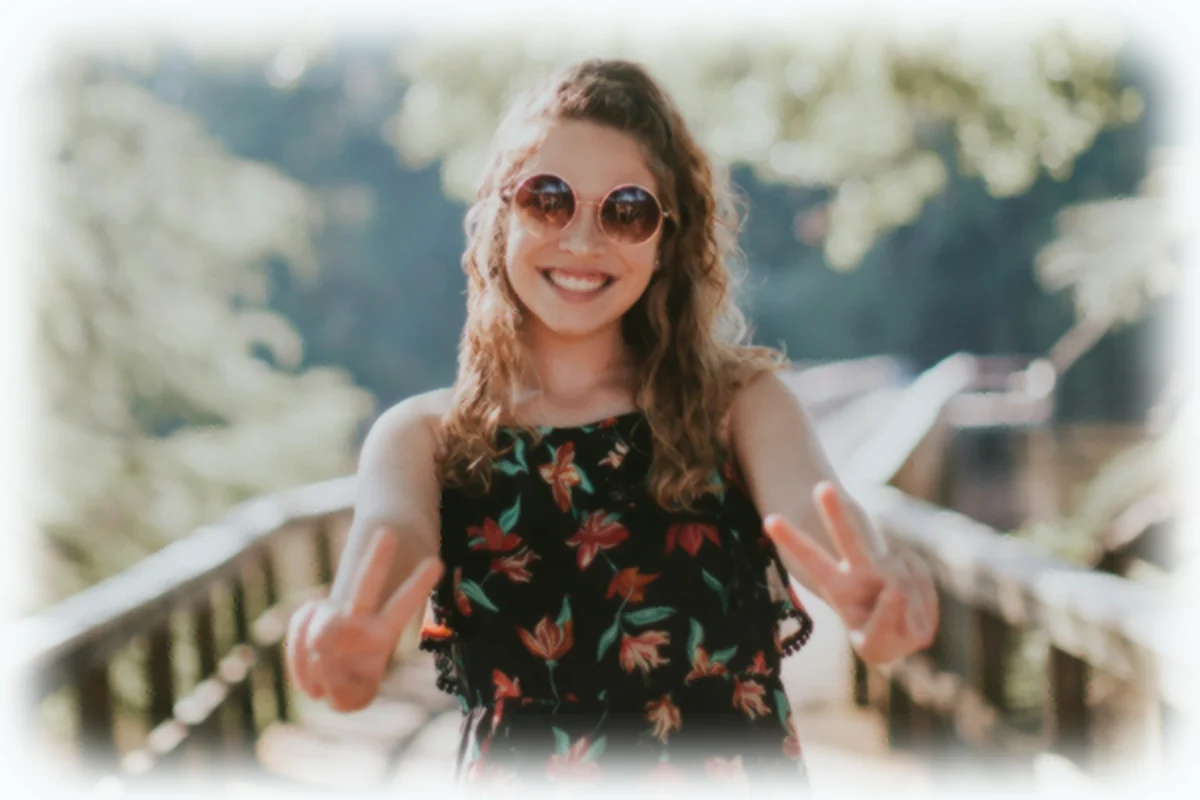 A smiling woman crossing a bridge and looking toward the camera
