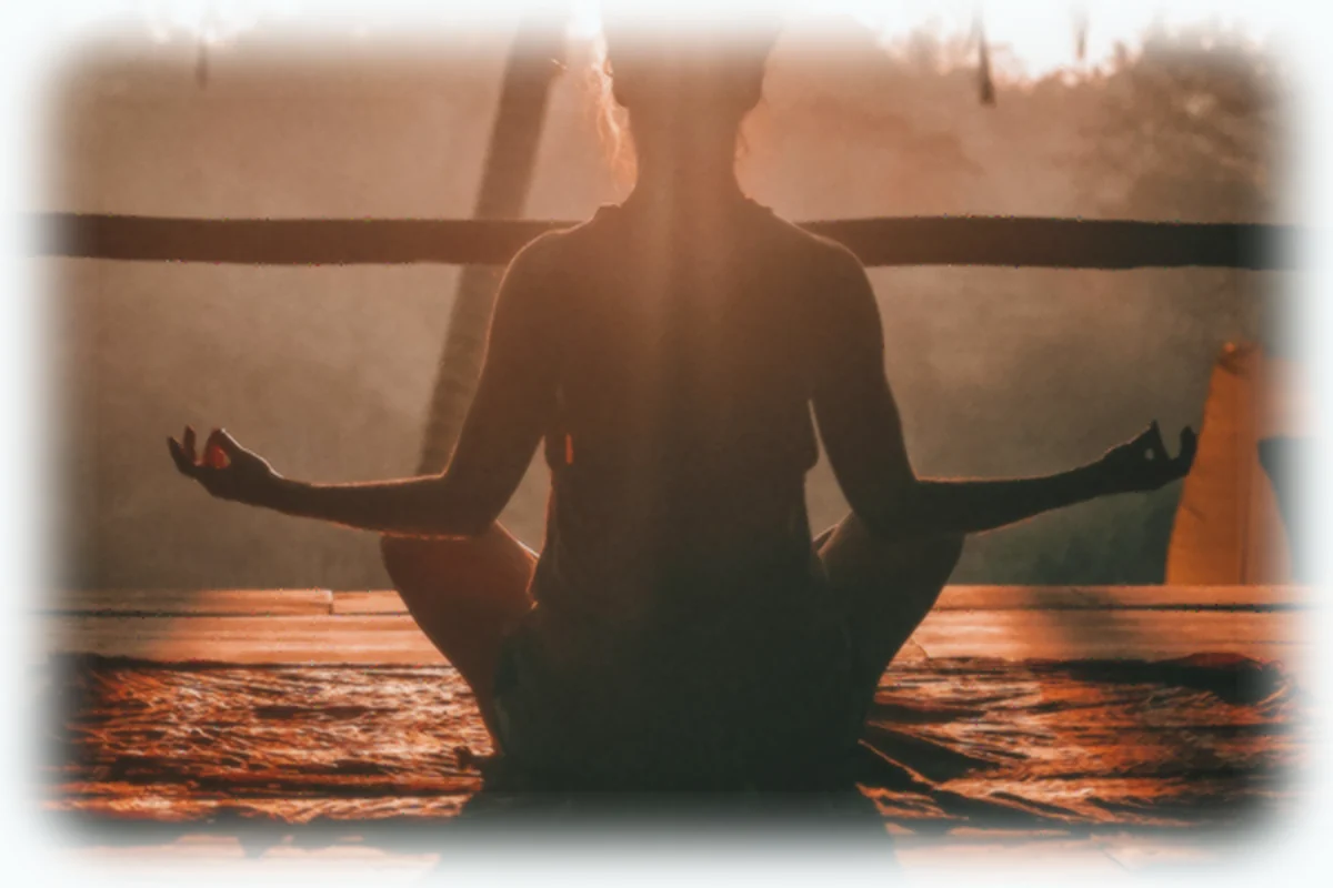A woman meditating outdoors in a calm setting