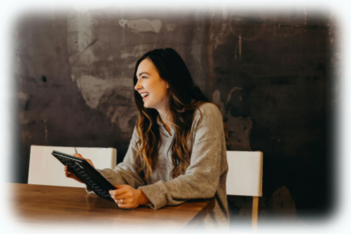 A smiling woman using a laptop in front of a blackboard