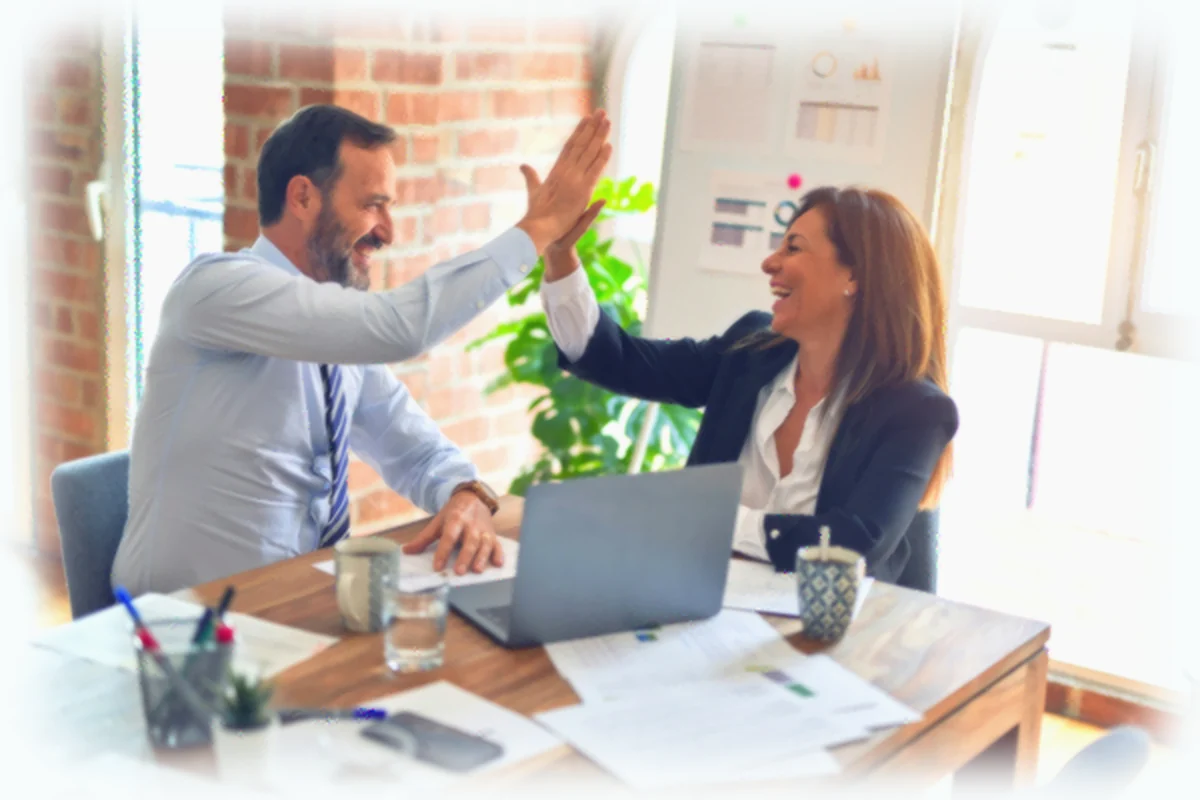 Two work colleagues high fiving each other in an office